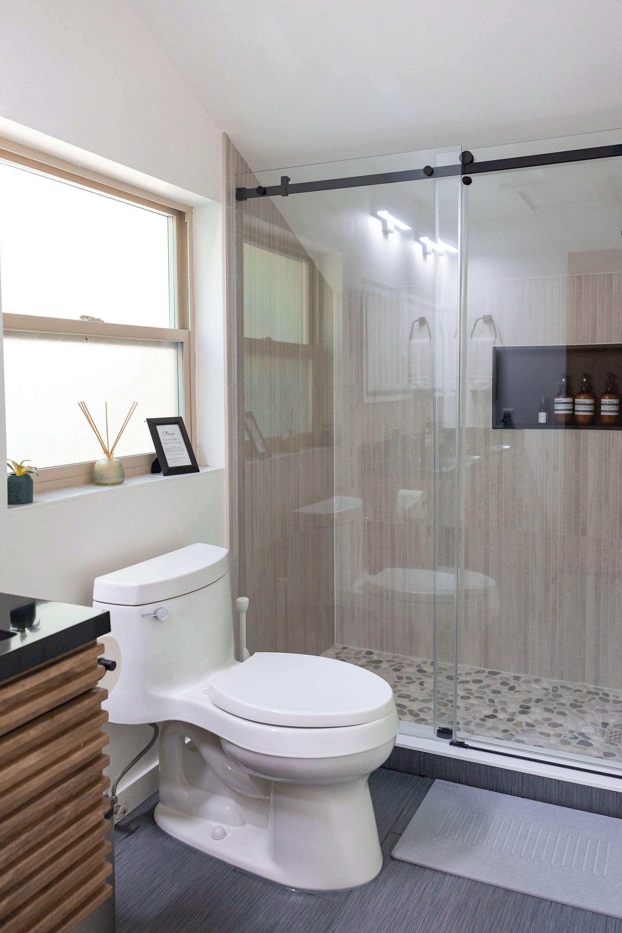 A modern bathroom with a toilet, a shower enclosure, and a vanity with a sink.
