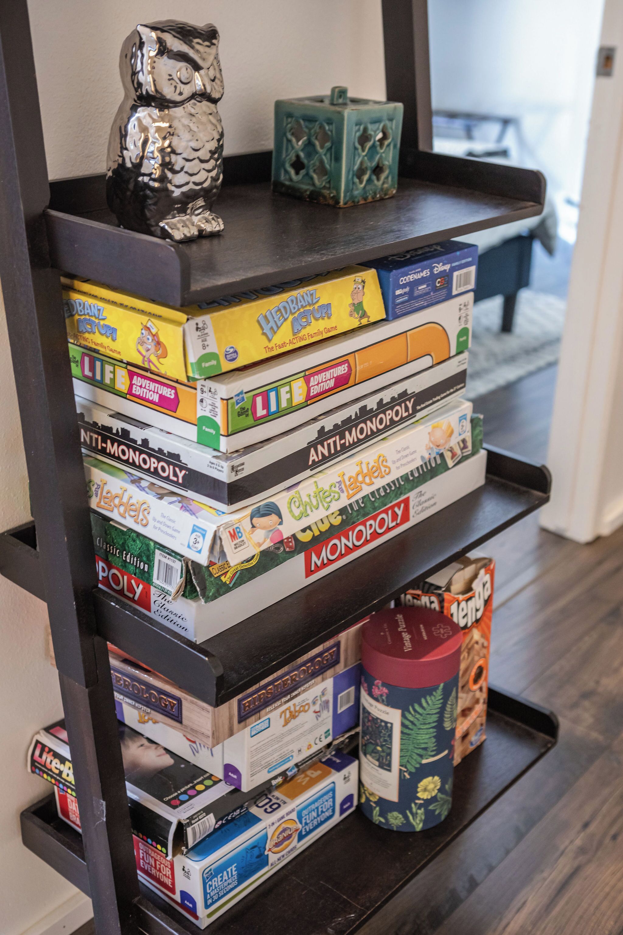 A shelf with various board games and a small owl figurine.