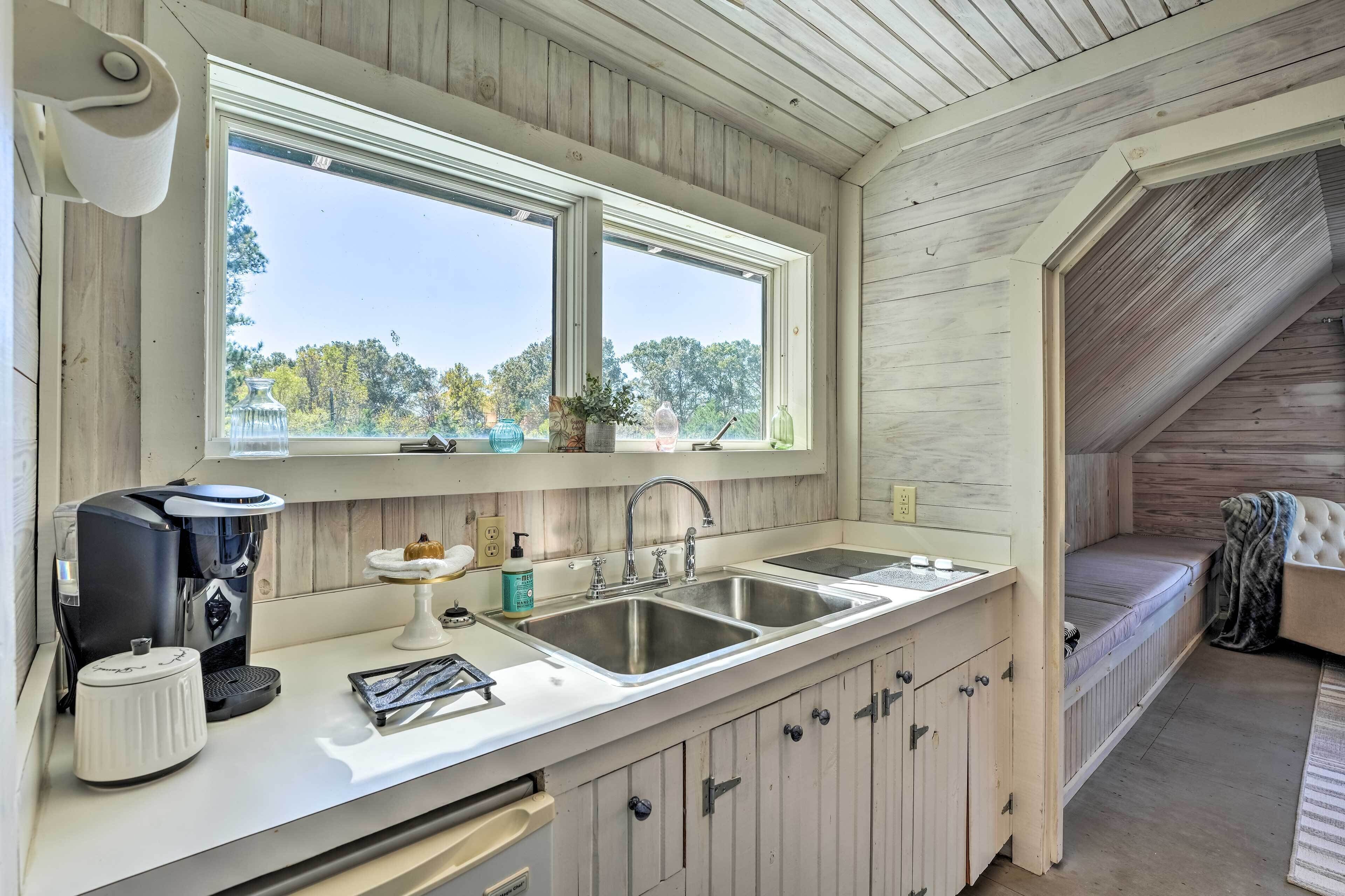 A kitchen with a coffee maker, sink, and window overlooking a scenic view.