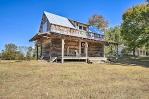 A rustic wooden cabin with a porch, a chimney, and a clear blue sky. - Unique Loft Cabin: Fire Pit & Fishing Access! (Bells)
