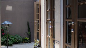 Un bâtiment doté de grandes portes vitrées, d’un lampadaire en métal et de plantes en pot.