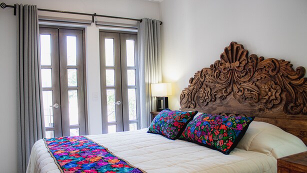 Une chambre à coucher avec un grand lit, une couvre-lit à motifs floraux et une tête de lit en bois.