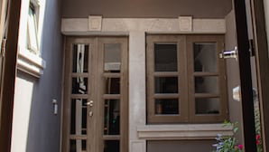 Un bâtiment doté d’une double porte d’entrée, d’un petit jardinier rouge et d’un balcon avec une rambarde en métal.