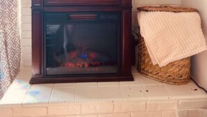 Une cheminée avec un manteau de couleur blanche, un petit panneau et des éléments de décoration végétale.