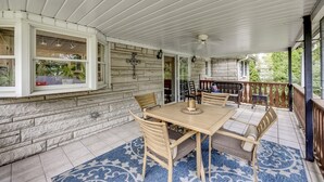 Een overdekt terras met een houten tafel en stoelen, stenen muren en uitzicht op de omgeving.