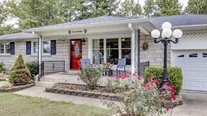 Een tweelaags huis met een veranda, een rode deur en een garage.