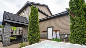 A spa area with a hot tub, stone pillars, and a wooden pergola. - Aspen Lodge by Revelstoke Vacations (Revelstoke)