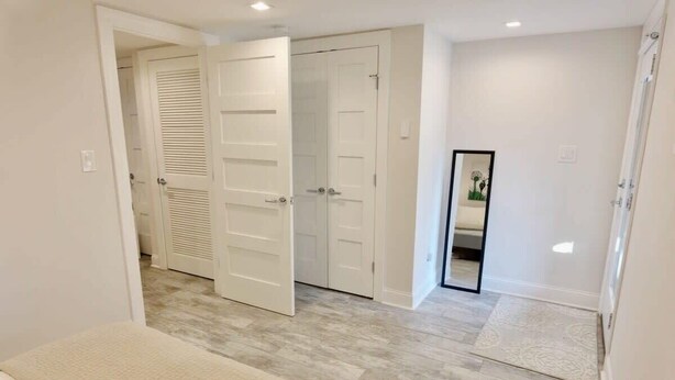 A hallway with a bench, a mirror, and two sets of double doors.