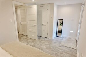 A hallway with a bench, a mirror, and two sets of double doors.