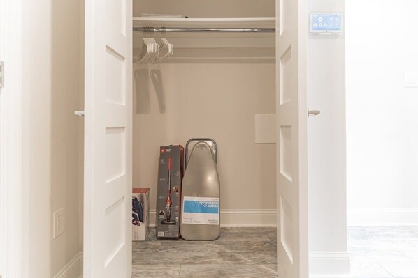 A hotel room with a closet containing a vacuum cleaner and a box.