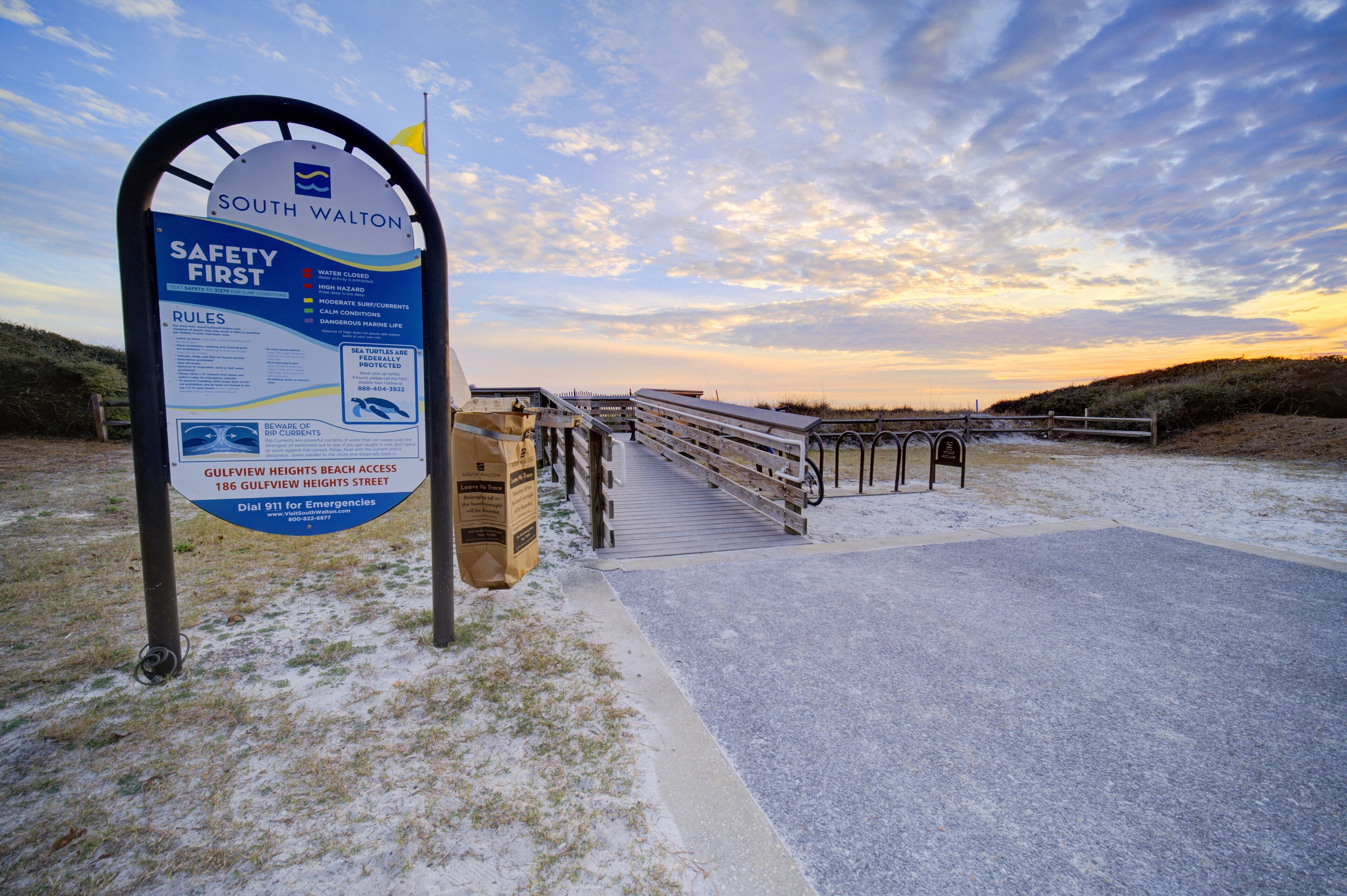 A safety sign at South Walton beach with emergency contact information.