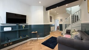Un salon moderne doté d’un téléviseur à écran plat, d’étagères intégrées, d’un canapé gris et d’un escalier menant à un autre niveau.