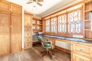 A kitchen with wooden cabinets, a green leather chair, and a window with a geometric pattern.