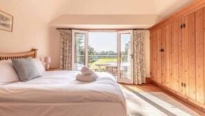 Un dormitorio con cama, armario de madera y balcón con vistas.