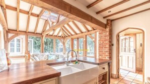Una cocina con un lavamanos grande, vigas de madera y vistas al exterior.