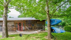 A cabin with a glass door, a hammock, and kayaks. - Log Cabin | Guadalupe River | Kayaks | Ping Pong (Seguin)