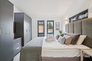 Een moderne slaapkamer met een bed, een kledingkast en een raam met uitzicht.