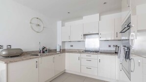 A modern kitchen with white cabinets, a stainless steel range, and a built-in oven. - 4-Bedroom Retreat in Slough - By Tempstay (Slough)