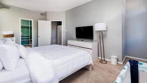 Una habitación de hotel moderna con una cama grande, un televisor, una lámpara de noche y un vestidor.