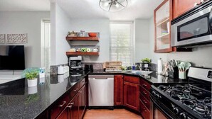 Una cocina moderna con armarios de madera oscura, encimera de granito negro, estufa de acero inoxidable y microondas integrado.