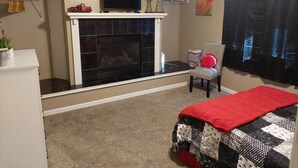 A living room with a fireplace, a television, a chair, and a bed. - NEW!!! The Uptown Oasis...seconds from Uptown Marion!!!  (Marion)