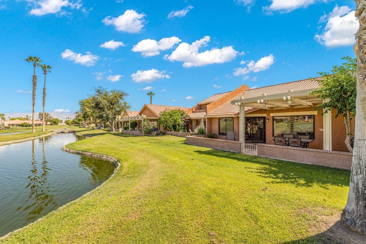 A residential area with a canal, houses with patios, and a clear blue sky.