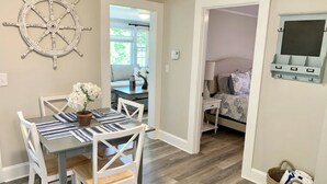 A dining area with a table and chairs, a potted plant, and a wall-mounted decorative wheel.