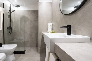 A modern bathroom with a shower, toilet, and sink. - Hotel Montoya (Punta del Este)