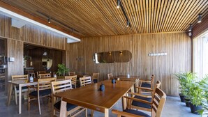A spacious dining area with wooden tables and chairs, a large mirror on the wall, and potted plants. - Hotel Montoya (Punta del Este)