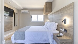 A modern hotel room with a bed, bedside table, and a mounted TV. - Hotel Montoya (Punta del Este)