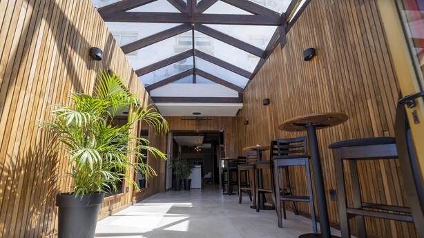 A modern interior with wooden walls, a high ceiling, and a central seating area with tables and chairs. - Hotel Montoya (Punta del Este)