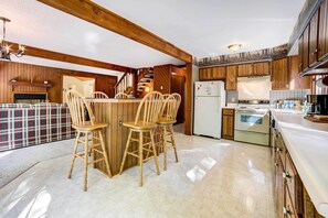 Eine Küche mit Holzausstattung, einer zentralen Kochinsel mit Sitzgelegenheiten, einem Kühlschrank und einem Herd.
