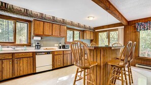 Une cuisine avec des meubles en bois, un coin bar et une grande fenêtre.