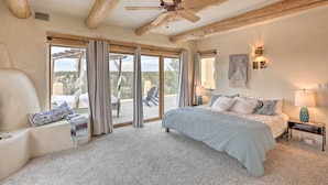 A bedroom with a large bed, a ceiling fan, and a view of the outdoors through a sliding glass door. - Adobe Home - River & Mtn Views w/ Hot Tub! (Redmond)