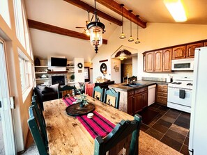 Una cocina amplia con armarios de madera, una isla central y un comedor con mesa y sillas de madera.