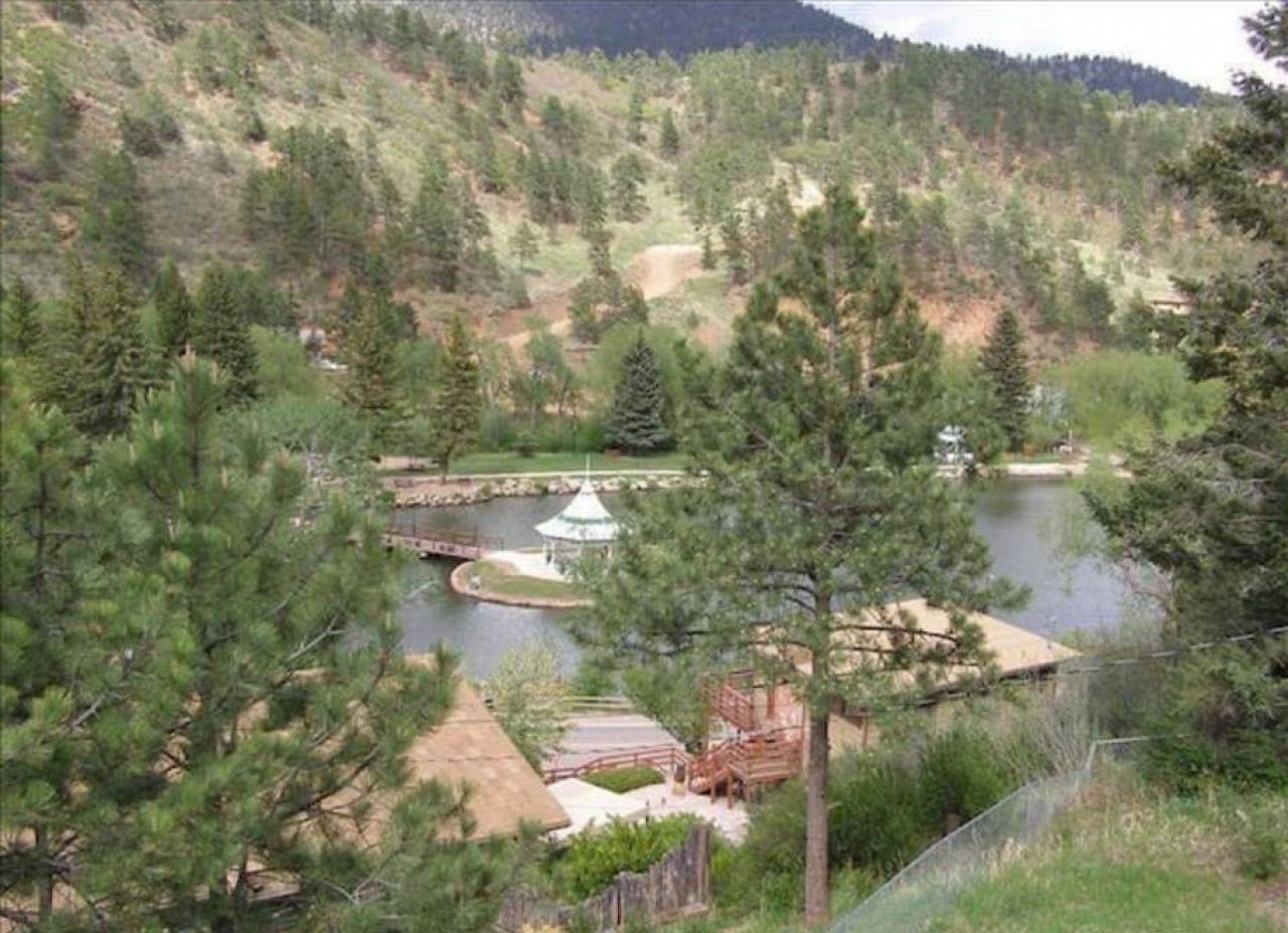 A lakeside view with a gazebo, a wooden deck, and a small bridge.