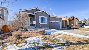 A residential house with a garage, a front yard with snow patches, and a clear blue sky. - Spacious 6-BDR Near USAFA with Mountain Views *Pet Friendly* (Colorado Springs)