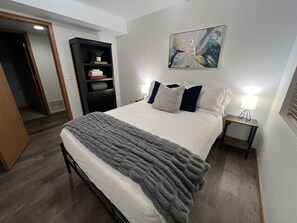 Ein Schlafzimmer mit Bett, Nachttischen, einem Kleiderschrank und einem Bild an der Wand.