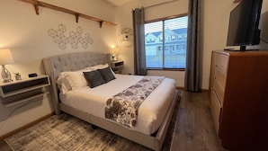 A bedroom with a bed, bedside tables, a dresser, a TV, and a window with curtains. - Spacious 6-BDR Near USAFA with Mountain Views *Pet Friendly* (Colorado Springs)