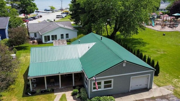 Een huis met twee verdiepingen, een groen dak, een garage en een overdekte veranda.