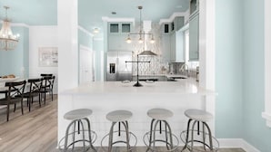 Une cuisine moderne dotée d’un îlot central, de tabourets de bar et de luminaires suspendus.