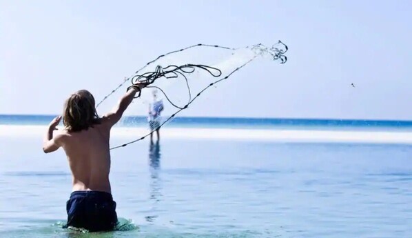 A person in the water holding a fishing net. - Seafoam: Private beach/Golf cart (Miramar Beach)