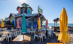 A wooden deck with outdoor seating and umbrellas, overlooking a beach. - Seafoam: Private beach/Golf cart (Miramar Beach)