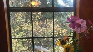 Ein Zimmer mit großem Fenster, einem Holztisch und einer Vase mit Blumen.