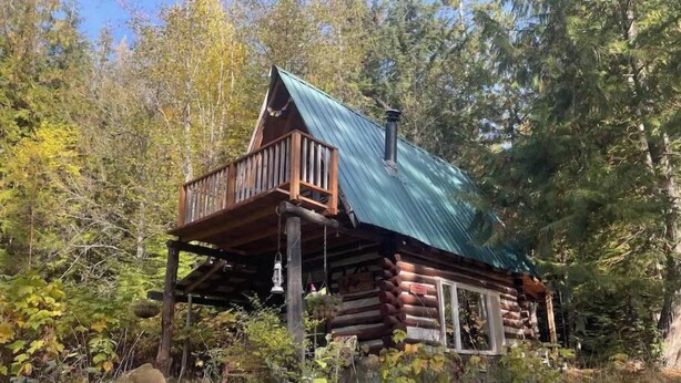 Eine Holzhütte mit Balkon, umgeben von Bäumen und Felsen.