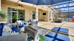 An outdoor patio area with wicker furniture, a ceiling fan, and a large umbrella providing shade.