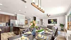 A modern kitchen with wooden cabinets, stainless steel appliances, and a dining area with a large table set for a meal.