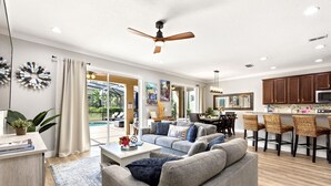 A spacious living room with a grey sofa, a coffee table, and a ceiling fan.