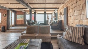 Ein großzügiger Wohnbereich mit einem großen Fenster, einem Sofa, zwei Sesseln und einem Couchtisch.
