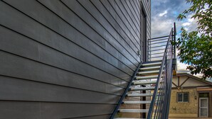 A metal staircase leading up to a building with horizontal siding. - Private guest house, king bed, work-from-home friendly, fully equipped kitchen (Denver)